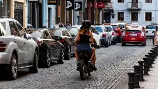 Dos personas subidas a una moto circulando por una calle