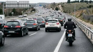 Un motorista circula por el arcén durante un atasco.