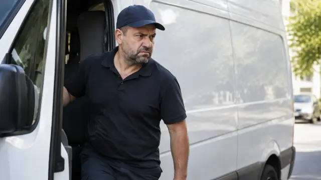 Transportista bajándose de su furgoneta de reparto