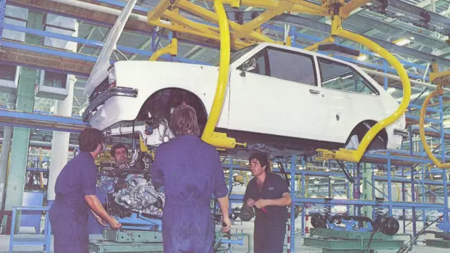Varios operarios colocan un motor en un coche en la planta de Almussafes en los años 70.